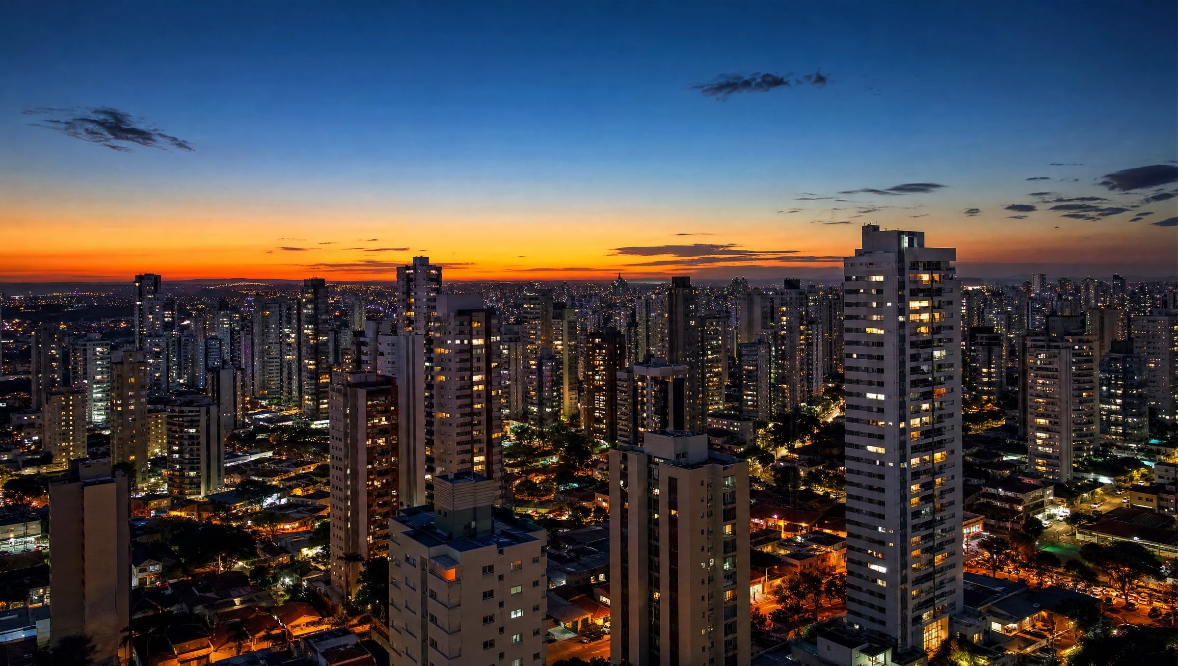 Skyline de Ribeirão Preto no crepúsculo, com as janelas dos prédios residenciais iluminadas